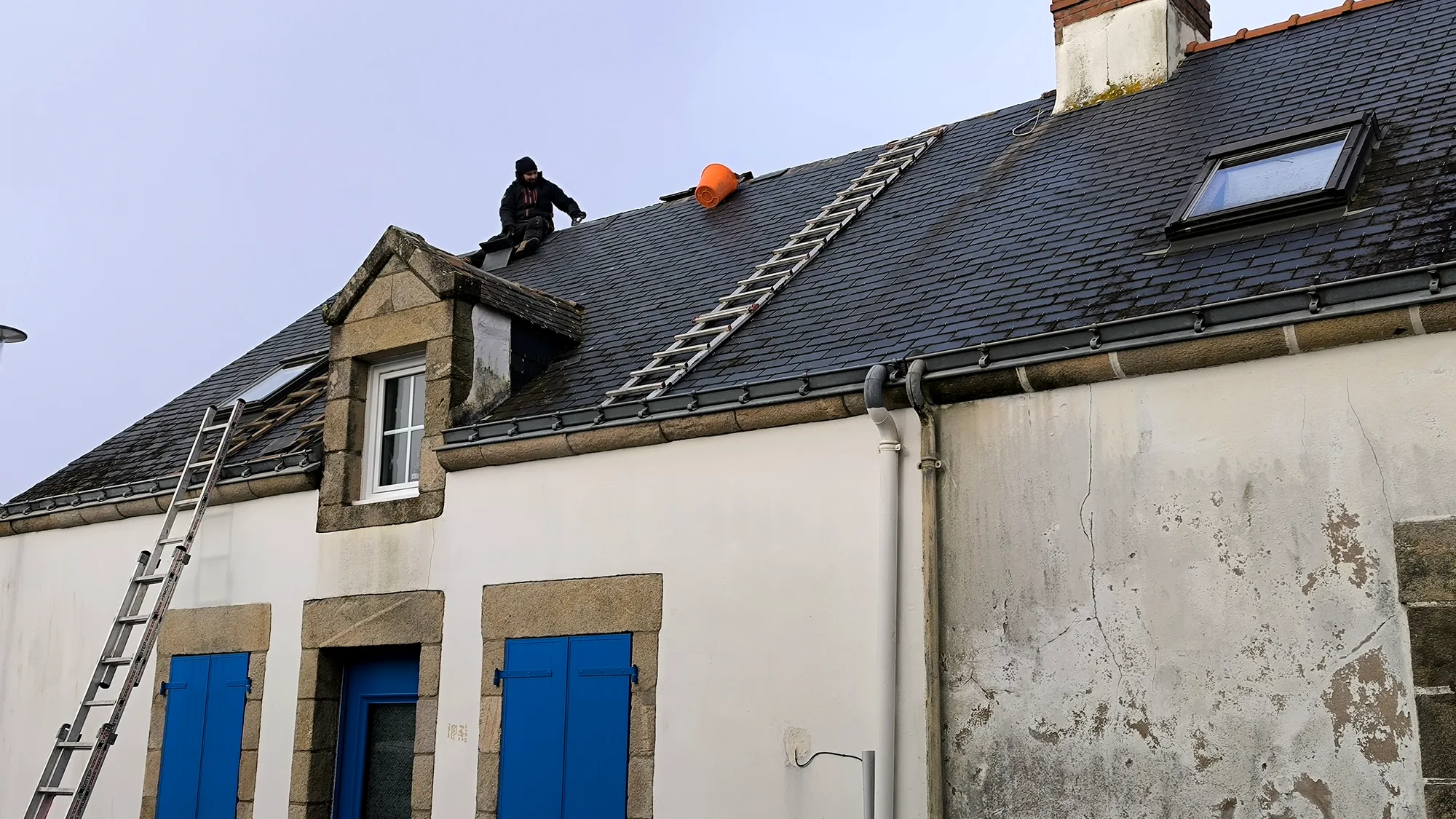 Couvreur de l’entreprise au faîtage pendant la dépose d’une couverture en ardoise